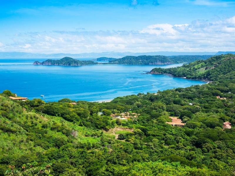 Houses within the rainforest with a blue sea in the background