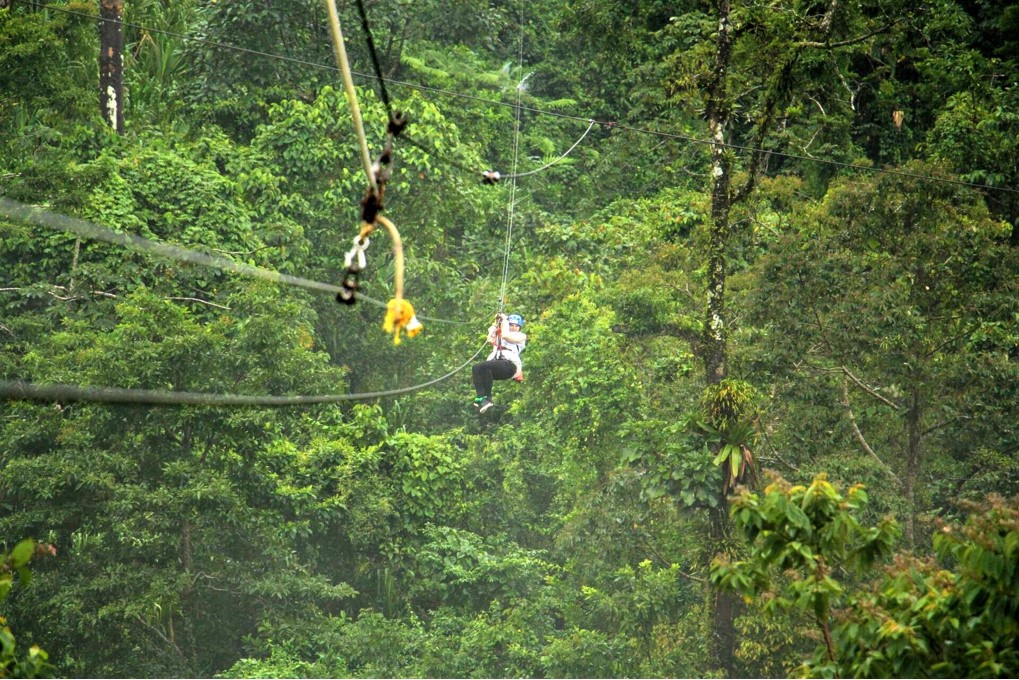 A women is zip lining in the middle of a rainforest