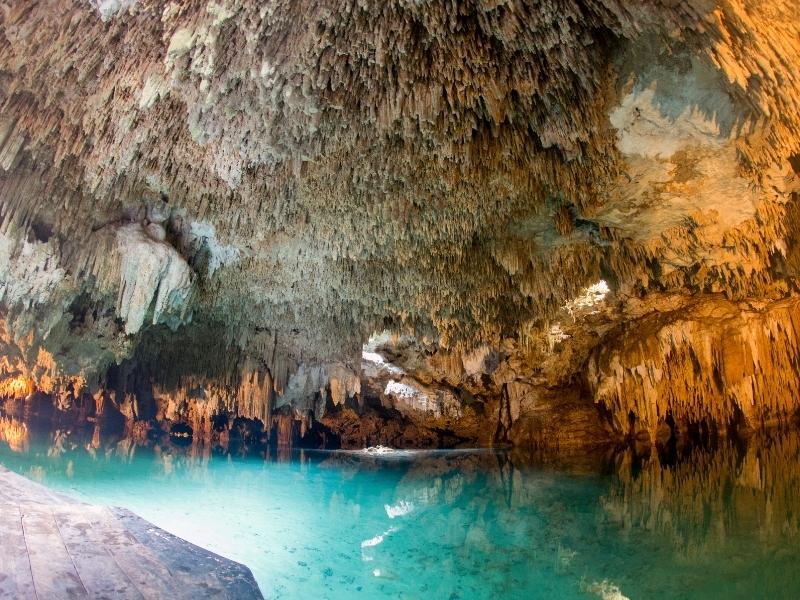 A large cave with a turquoise lake inside.