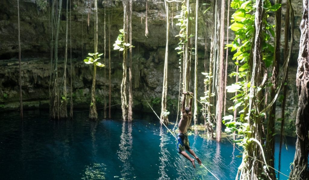 Blue water high cliff and vines are hanging from the top.