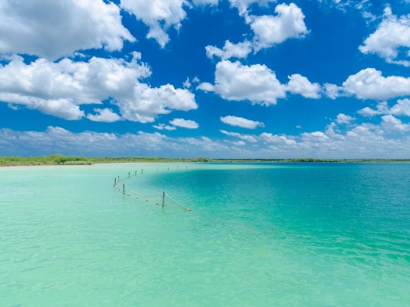 Shallow light blue lagoon and a blue white cloudy sky.