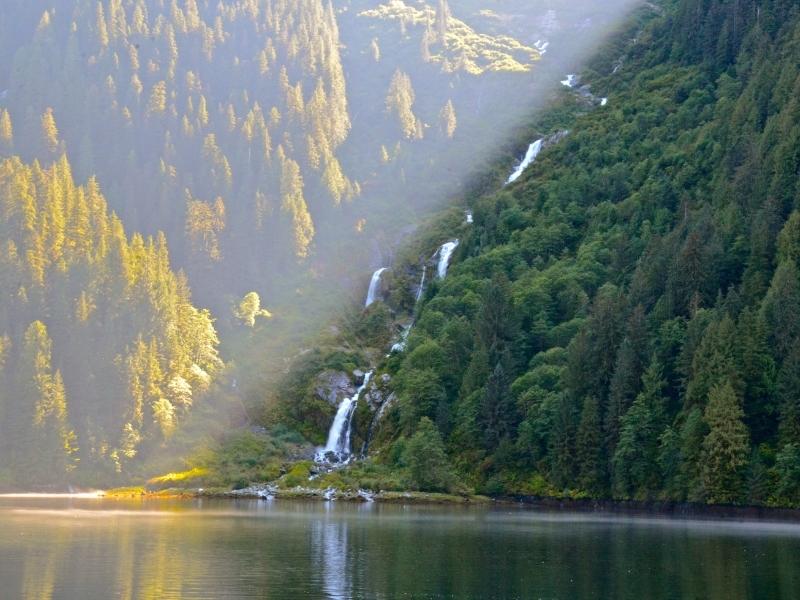 Cloudy green forest around a lake side with a waterfall 