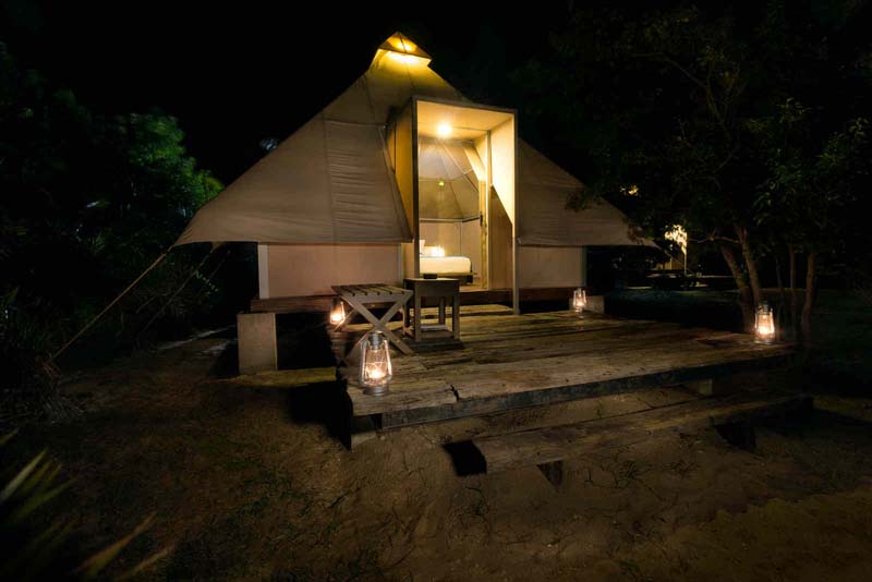 A tent with a large glass window on an elevated wooden platform. 