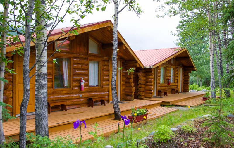 Two wooden cottages next to each other with front terasse. 