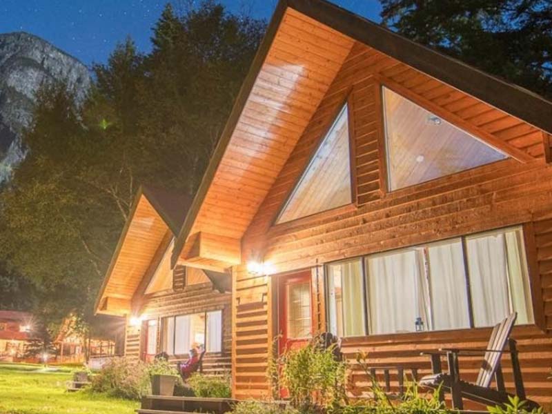 2 wooden cottages with large windows right next to each other. 