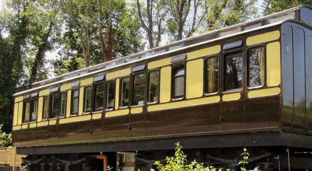 An old brown and yellow train carriage with many windows in a middle of a forest used as an accommodation not as a train