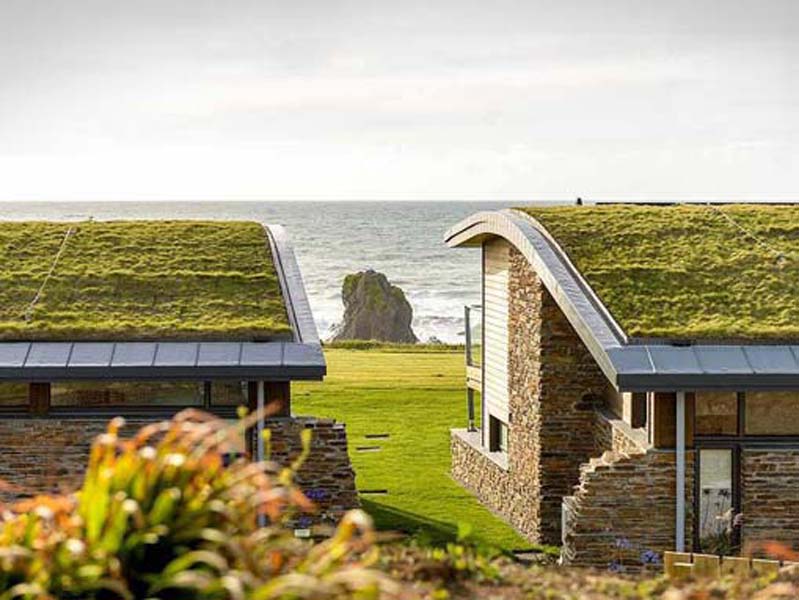 2 stone cottages with grass roof facing towards the cliffs and the ocean. 