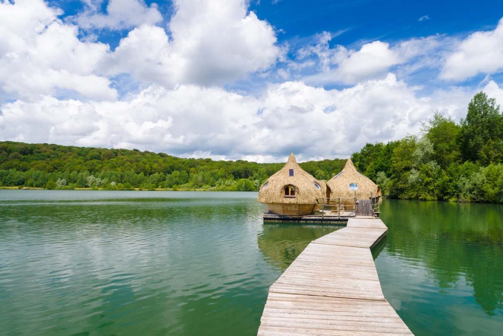 A floating small hut on a lake with a long boardwalk to it.