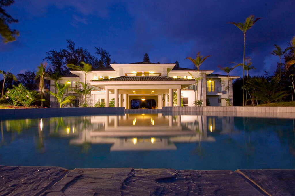 Nicely light white building with a swimming pool in front by night.