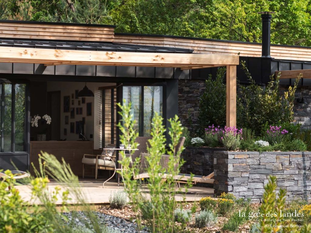 A stone and wood house surrounded by green trees.