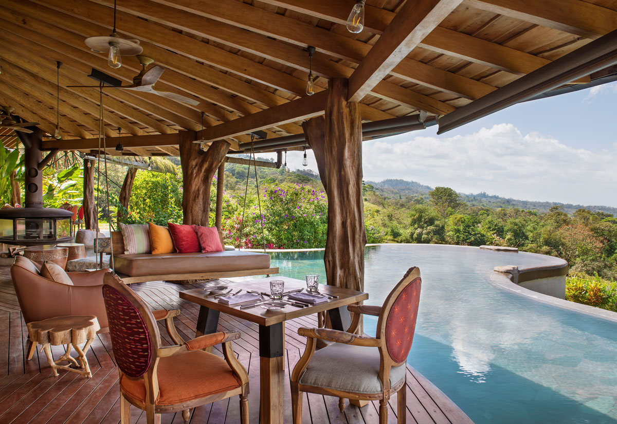 A terrace with a swimming pool and a view over the rainforest.