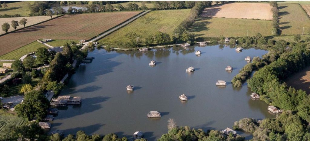 Several floating huts in a lake from above.