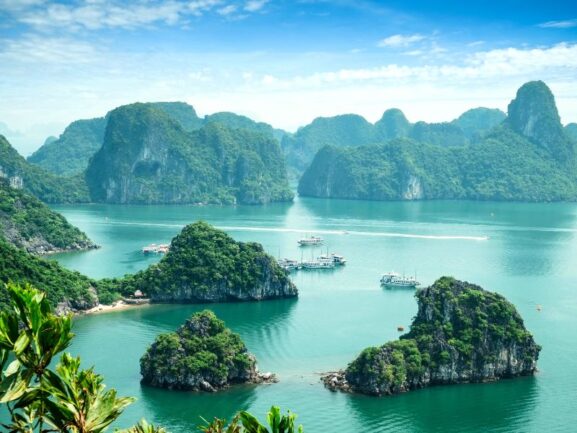 Halong Bay, turquoise sea with rocks rising from it covered with green vegetation.