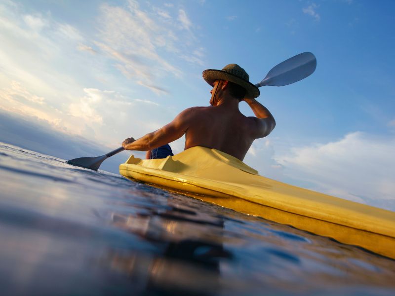 A man in a yellow kayak paddling.