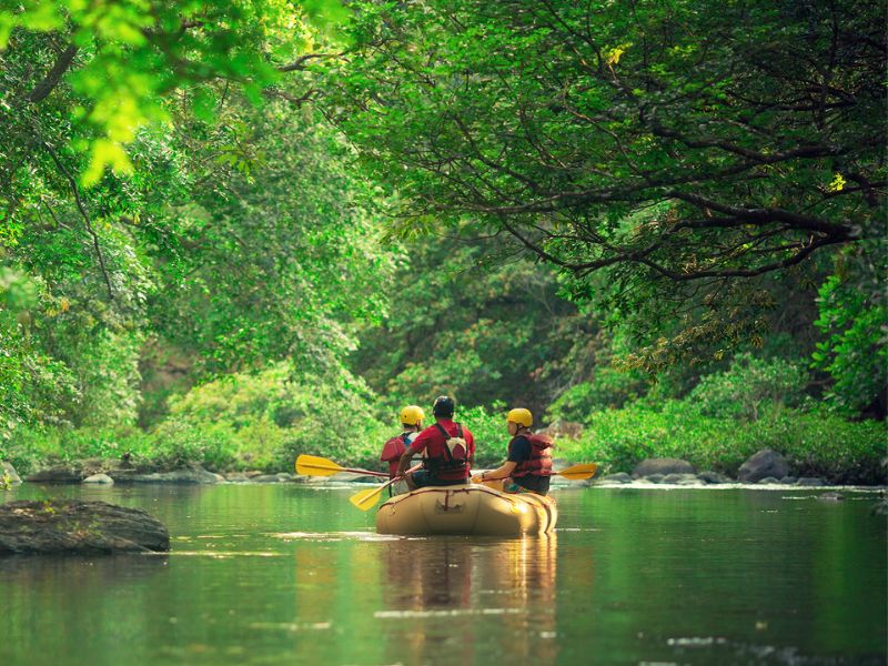 3 people on a raft floating on a calm river