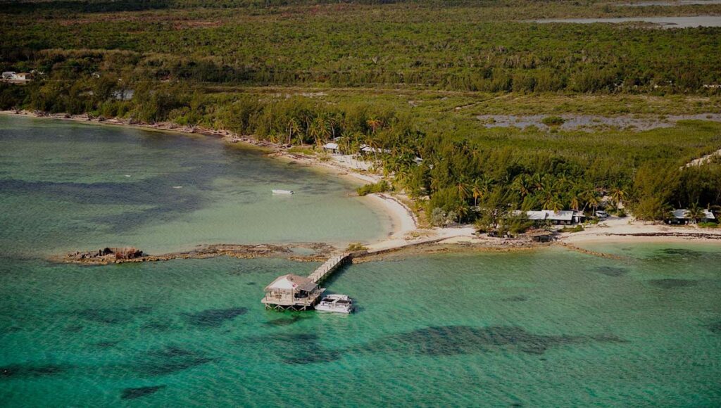 Blue green bay with a rocky shore and small buildings