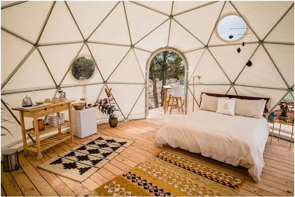 A dome house with bed table chair and rugs.