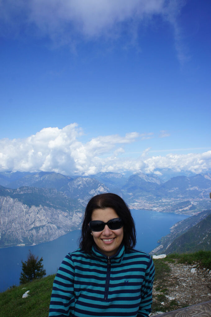 A woman sitting on a mountain. Behind her is a lake. 