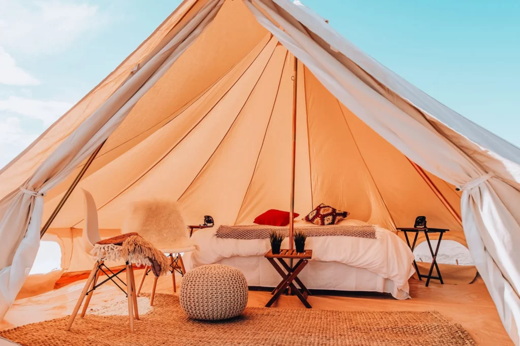 A large white tent with cosy double bed and some small furnitute.