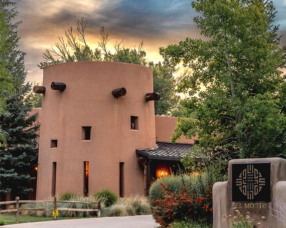 A column-shaped sand colored building with trees around it.