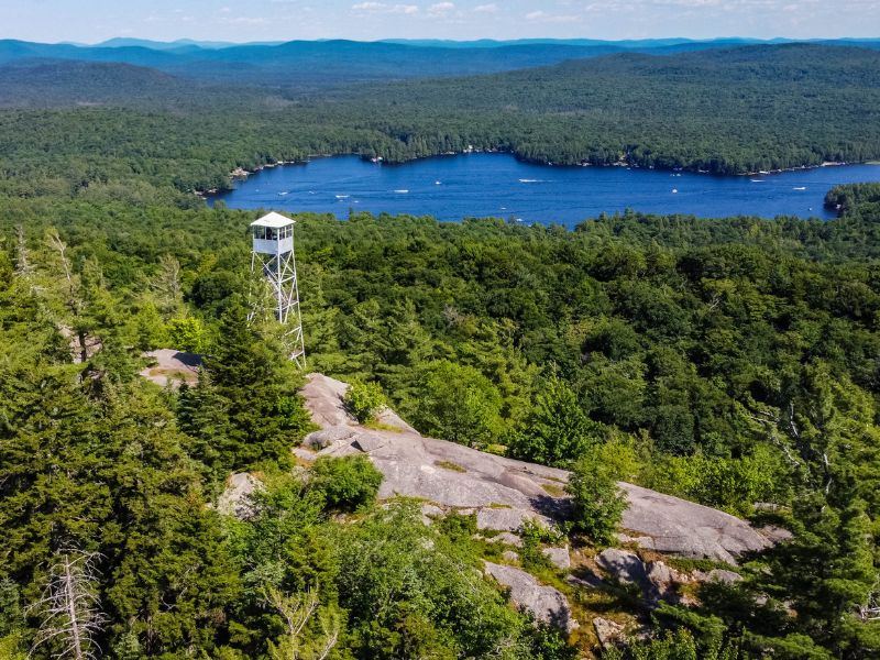 Mountains covered with green trees with a lake in the background and a viewpoint tour.