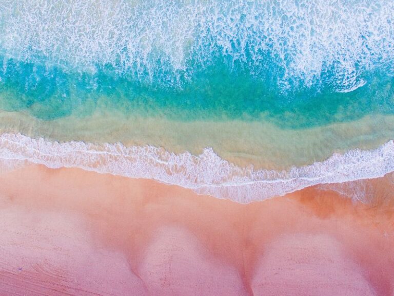 Pink sand beach from above with azure waves