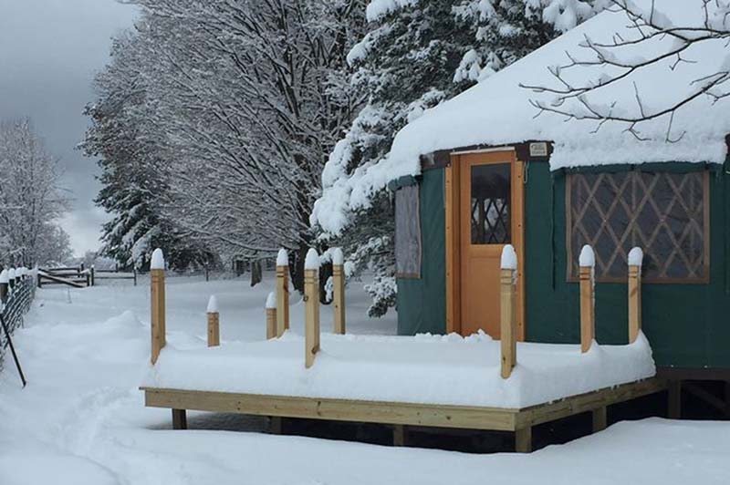 Green and yellow yurt covered in snow
