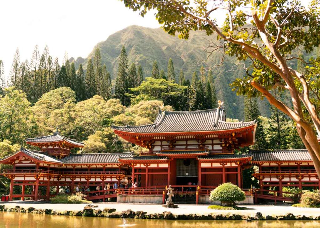 A Japanese wooden temple with a lake in front and mountains in the background