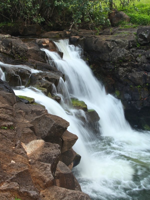 Small cascades flowing down on dark brown rocks
