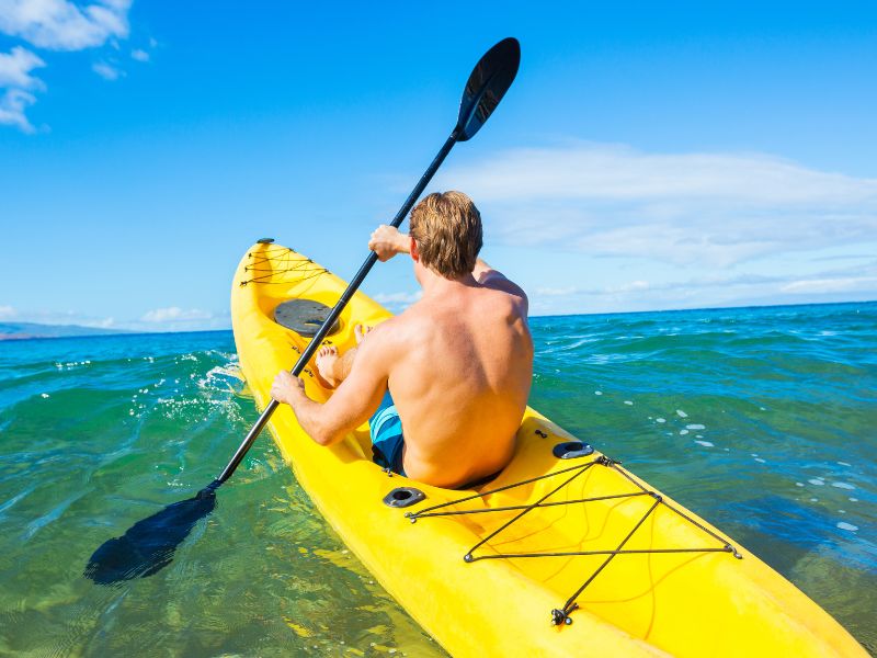 Man in a yellow kayak in the water. 