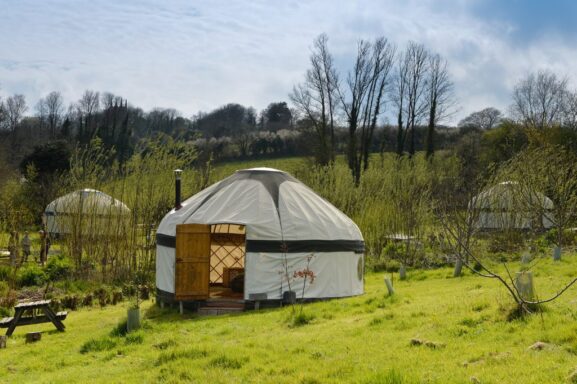 Three white yurts in a grass.