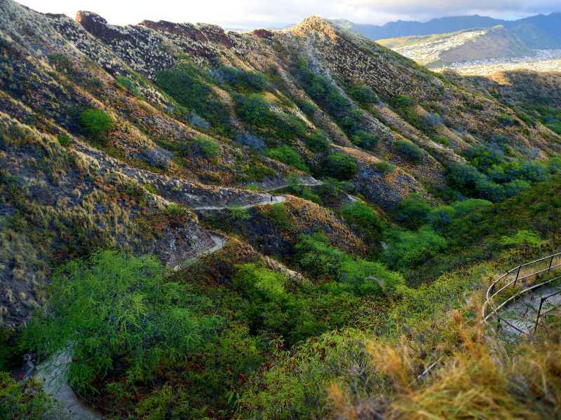 Rocky volcanic terrain with green vegetation and a walking trail