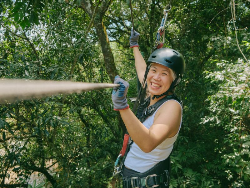 A women with climbing gear and helmet is holding a zip line.