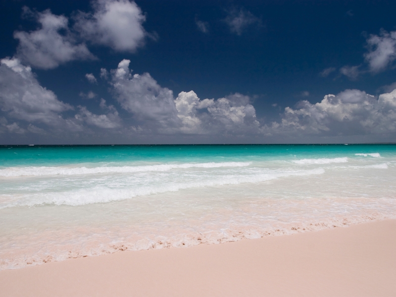 Gentle waves on a pink sandy beach.