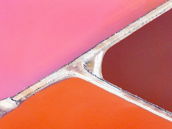 3 different shades of pink lake divided by thin strip of land.