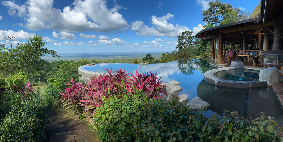 Swimming pool and open-air building overlooking a view.