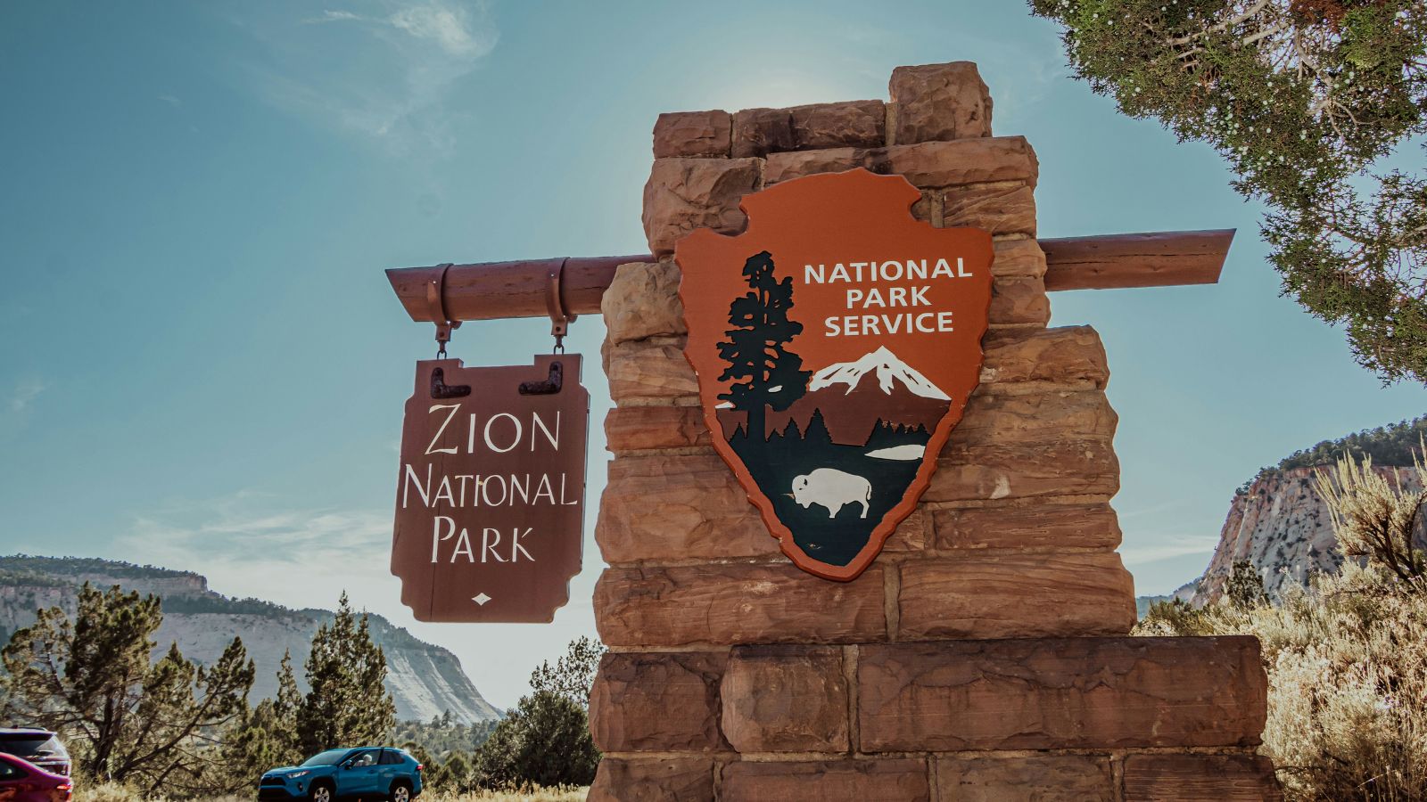 A large post with wooden sign saying zion national park