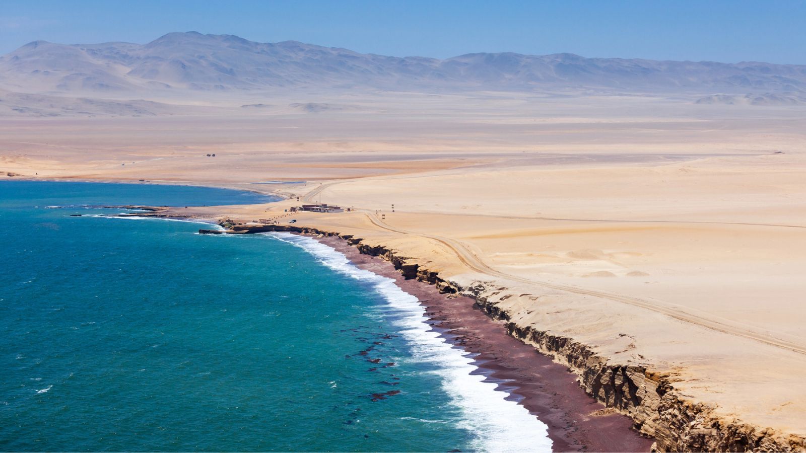 Dark red almost crimson beach and light brown barren cliffs.