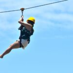 Woman ziplining white short yellow helmet