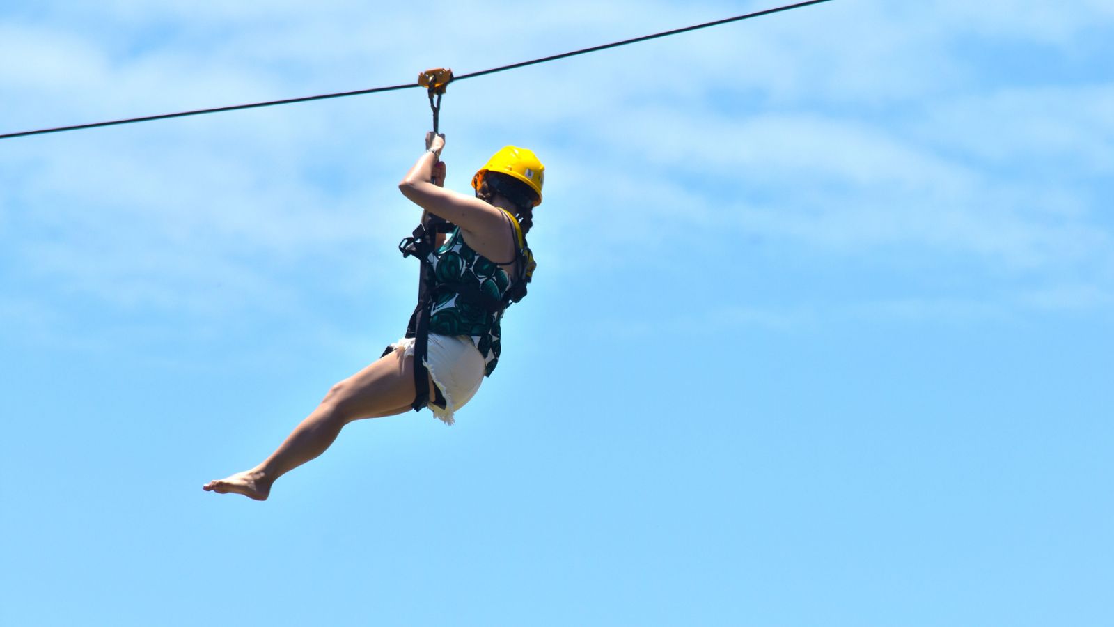 Woman ziplining white short yellow helmet