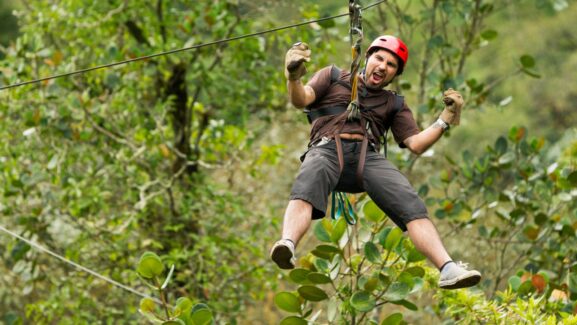 Ziplining male brown clothes red helmet