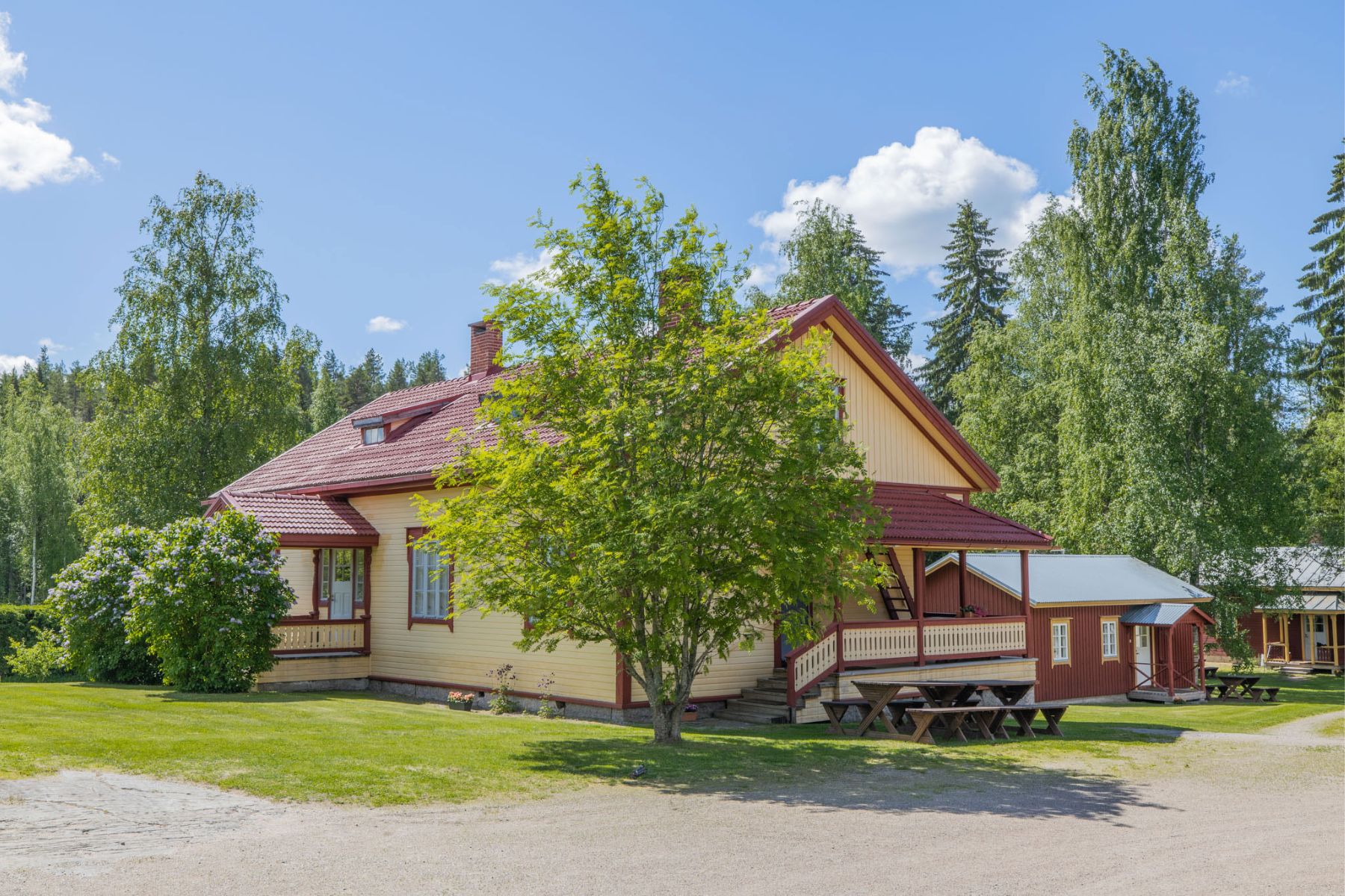 Red wooden house with a porch surrounded by small red cottages