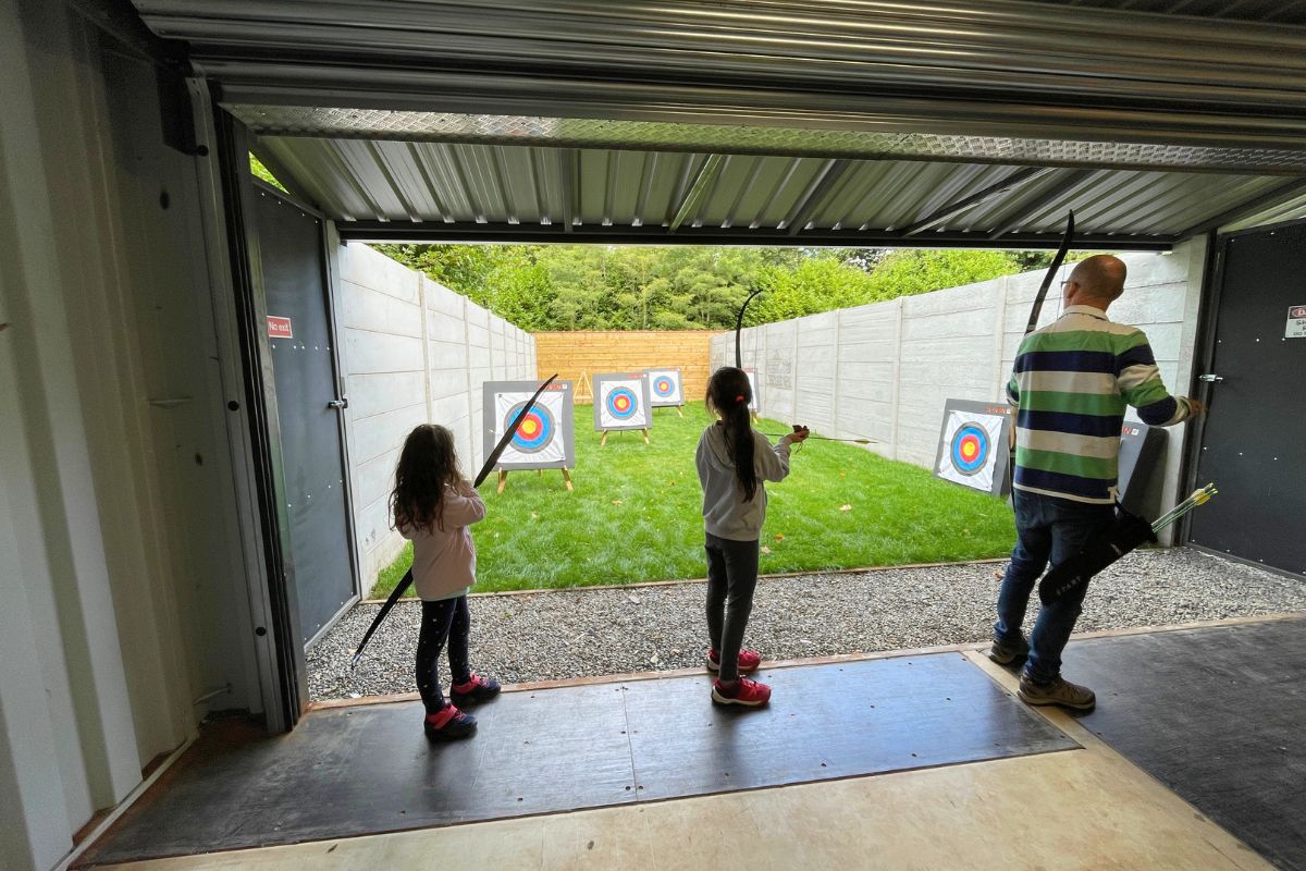 Three people are holding bows and arrows and about to shoot colored target circles.