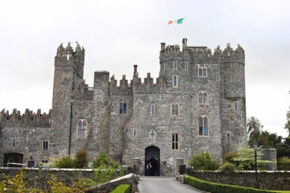 12-century medieval castle with grey walls and an Irish flag at the top